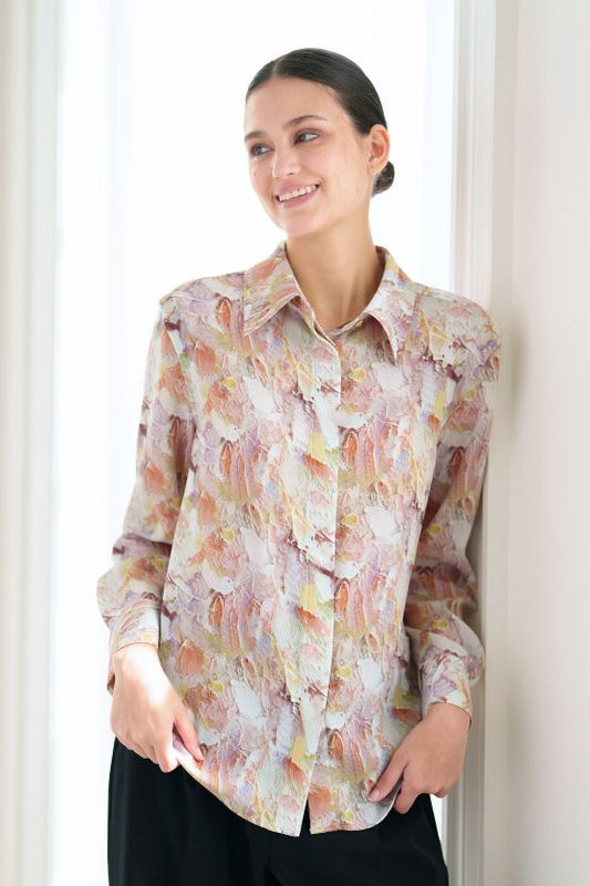 Portrait of a model wearing a patterned long-sleeve blouse.